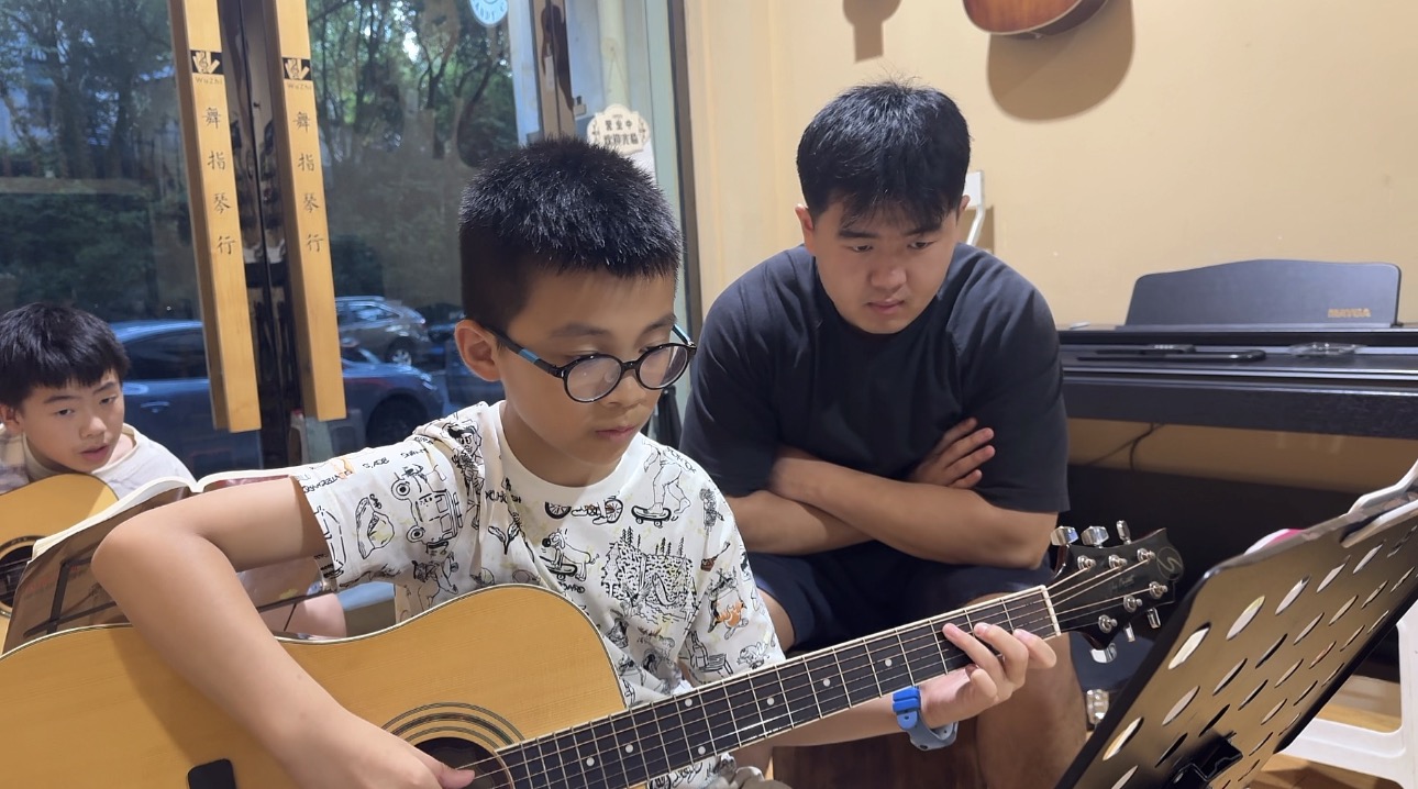 Zhang Zhebin guiding a student during guitar practice